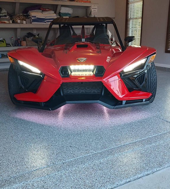 Red three-wheeled roadster on a gray flake epoxy garage floor